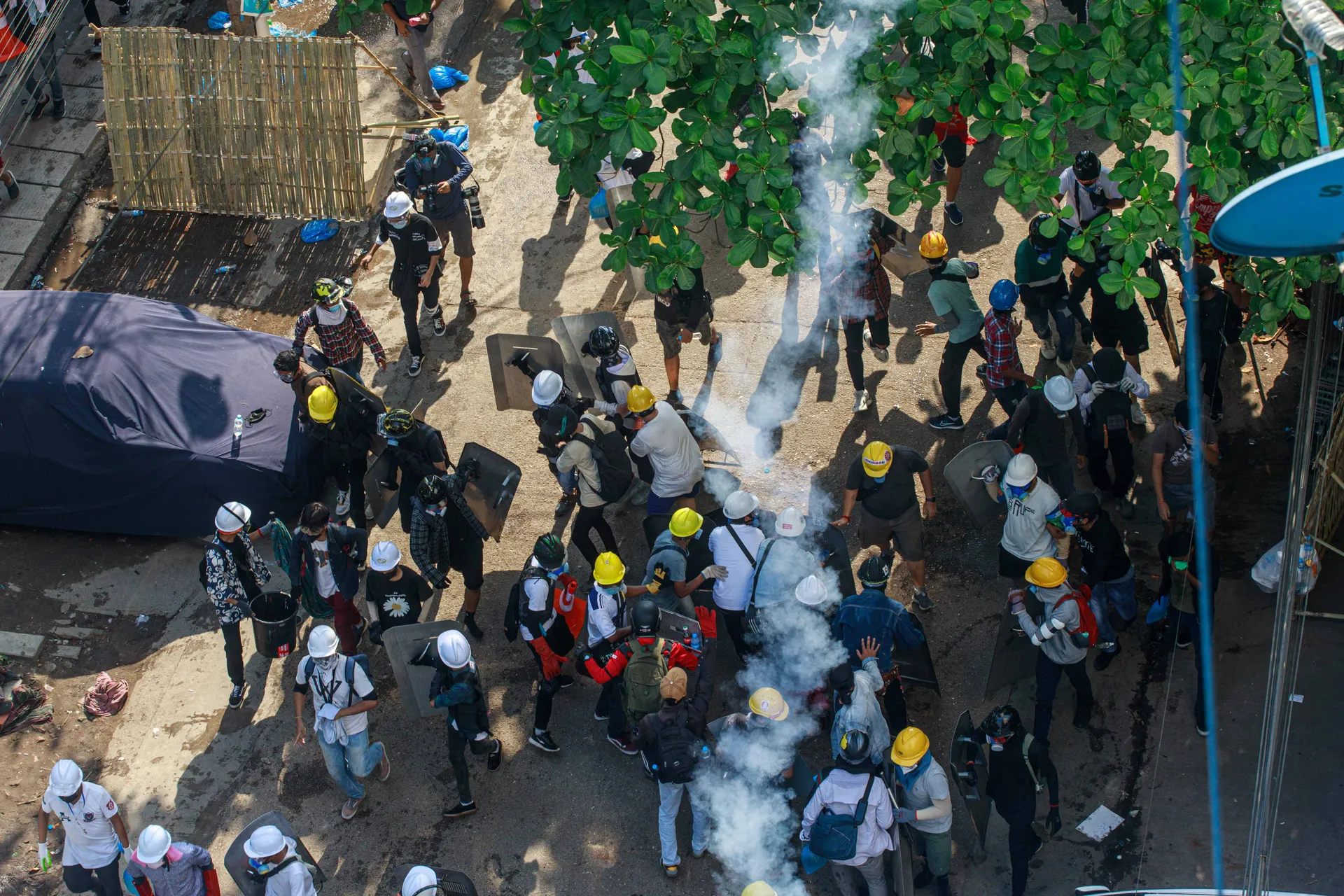 protesters takes a defensive stance as police fire rubber bullets and tear gas in Yangon. The tense scene reflects the ongoing clashes between demonstrators and security forces during the unrest. Photo - TaMwe