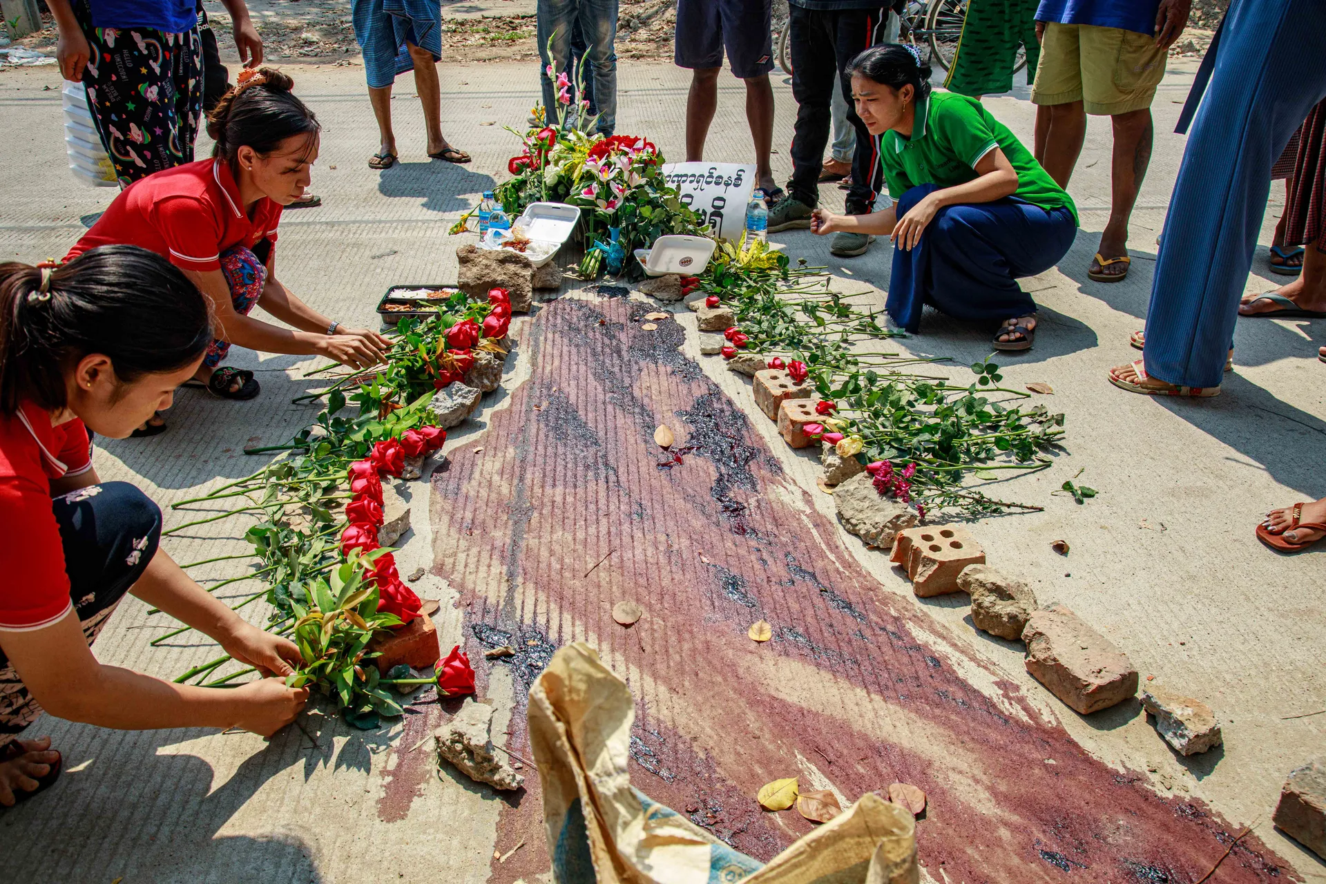 A solemn scene where people gather to pray and pay tribute to Chit Min Thu, a 24-year-old who was tragically shot and killed with live ammunition by the military on March 11, 2021. The location serves as a poignant reminder of the violence and loss experienced during the unrest. Photo - TaMwe
